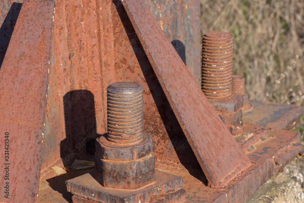 Fragment of a rusty metal construction with bolts and nuts. A High-voltage power transmission tower. Power engineering. Fragment of a rusty metal construction with bolts and nuts. A High-voltage power transmission tower. Power engineering.
