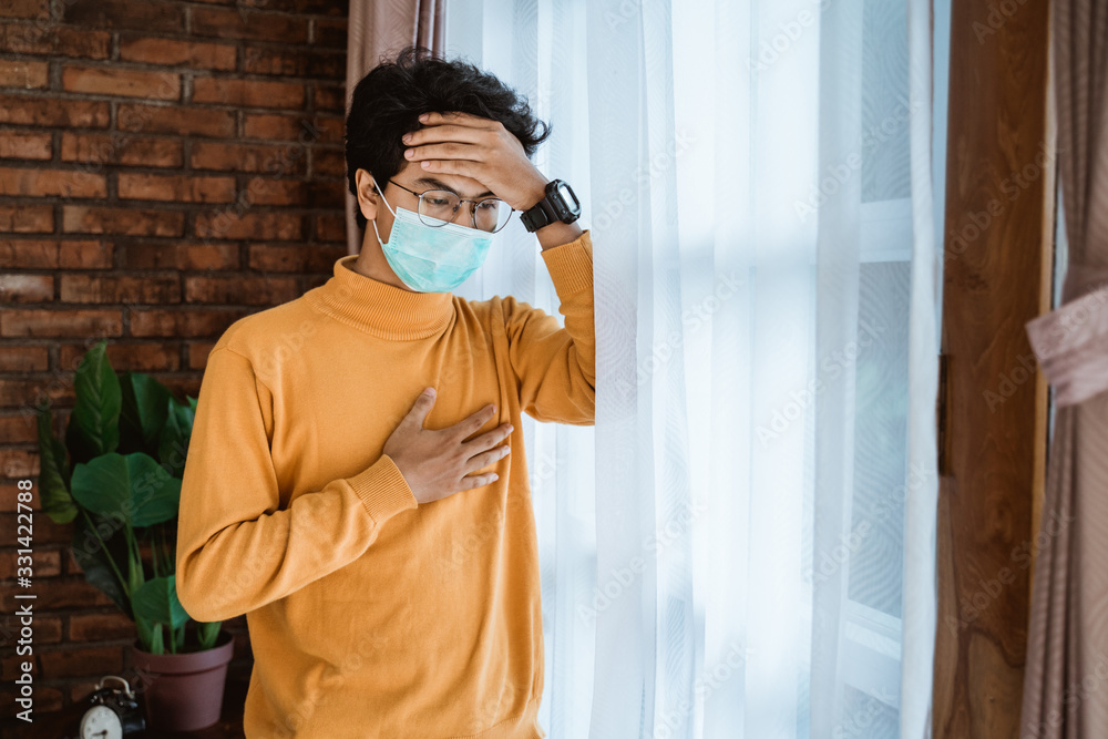 man with face masks looking out the window during social distancing man with face masks looking out the window during social distancing