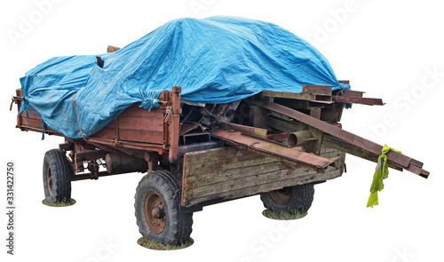 Old red rural tractor trailer cart wuith wooden logs and blue  tarpaulin plastic  cover isolated on white photo
