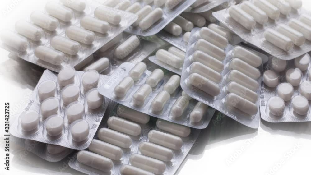Closeup shot of different pills falling on table with tablets , pharmaceutical industry concept Closeup shot of different pills falling on table with tablets , pharmaceutical industry concept