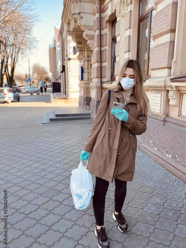 Naklejka premium young woman in the city in a protective mask and gloves against a coronavirus. Covid 2019. Covid 2020.