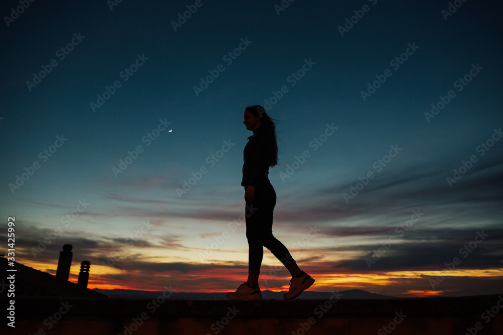 Woman silhouette in village at sunset. Young woman admiring panoramic view at sunset in Italy, a popular tourist destination in Italy. Woman silhouette in village at sunset. Young woman admiring panoramic view at sunset in Italy, a popular tourist destination in Italy.