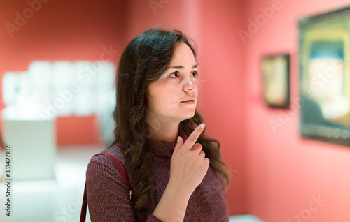 Glad woman watching at art collection exhibition