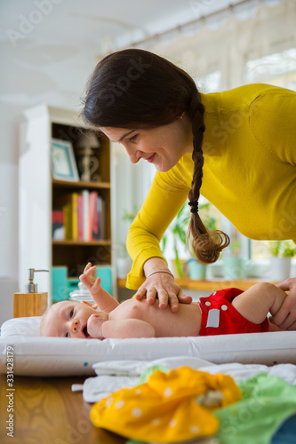 Mother changing reusable diaper or nappy. Reusable diaper and infant. Baby with eco diaper. 