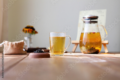 Traditional heral tea with glass teapot, cup, dried rose buds. Flowers on wooden table at home,sunlight background, selective focus, copy space