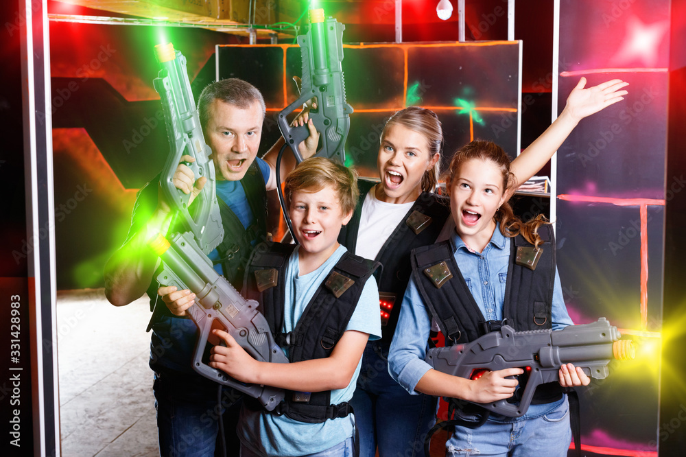 Group of happy teenagers and adults with laser guns posing toget