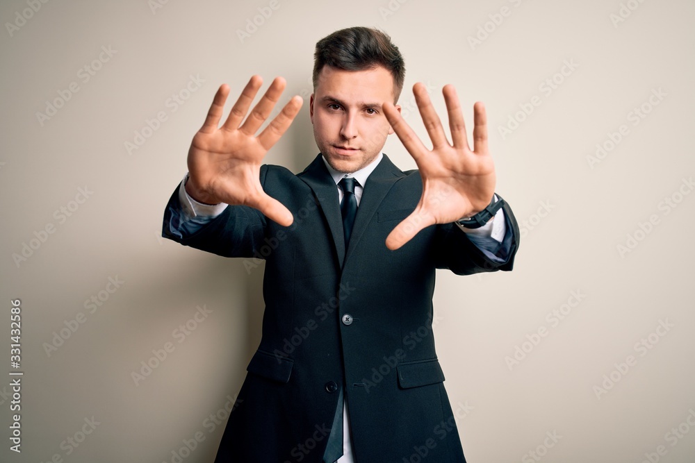 Young handsome business man wearing elegant suit and tie over isolated background doing frame using hands palms and fingers, camera perspective Young handsome business man wearing elegant suit and tie over isolated background doing frame using hands palms and fingers, camera perspective