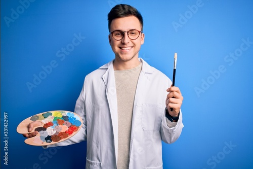 Obraz na płótnie Young handsome caucasian artist man holding paintbrush and painter palette with