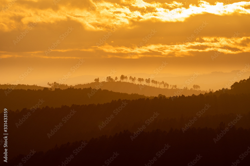Sunset with orange sky and many hills in layers