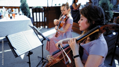 String Quartet In Lilliac Dresses Taking Part In Classical Event Or Wedding Ceremony Outside Summer Terrace