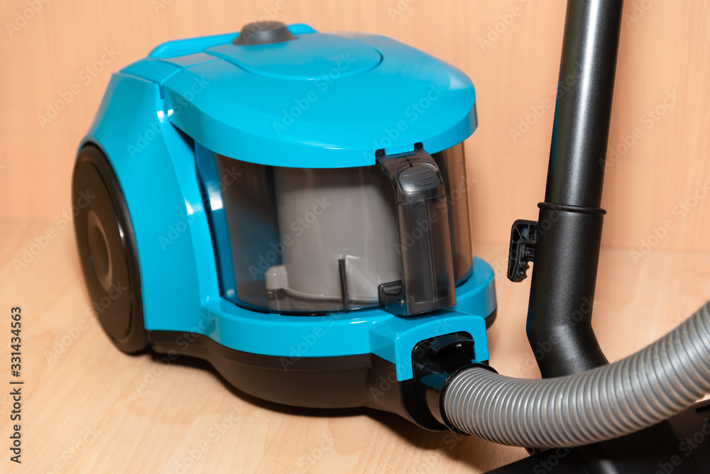 vacuum cleaner without a bag of blue color stands on the floor of the