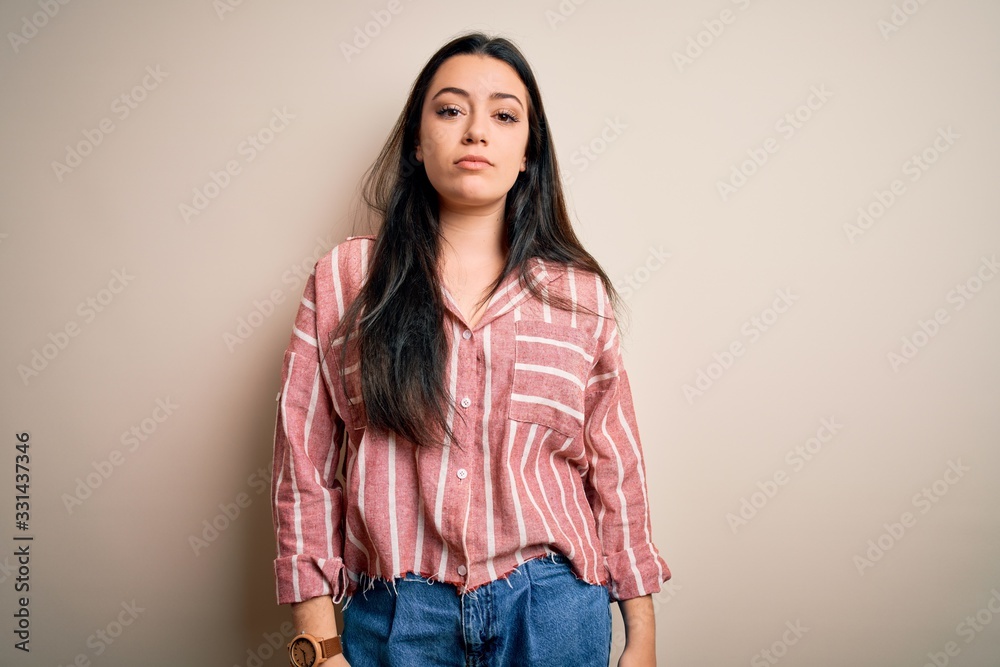 Young brunette woman wearing casual striped shirt over isolated background Relaxed with serious expression on face. Simple and natural looking at the camera. Young brunette woman wearing casual striped shirt over isolated background Relaxed with serious expression on face. Simple and natural looking at the camera.
