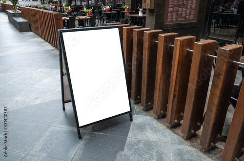 Blank white outdoor advertising stand/sandwich board mock up template. Clear street signage board placed by an outdoor dinning area of a restaurant. Background texture of standee on street. photo