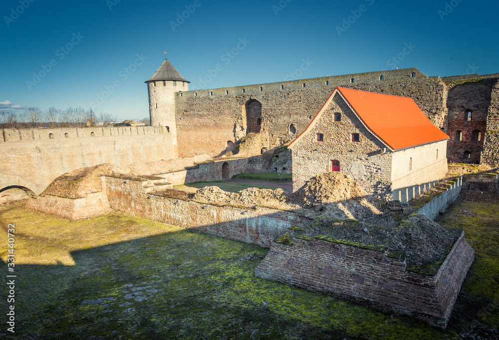 Old fortress. Walls and towers of an old castle. Medieval buildings partially destroyed. View of the old fortress in the spring.