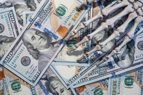 Skeleton hand lying on the dollars.