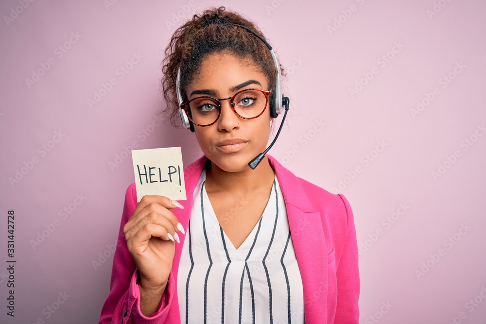 African american call center agent girl using headset holding reminder with help message with a confident expression on smart face thinking serious African american call center agent girl using headset holding reminder with help message with a confident expression on smart face thinking serious