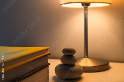 Bedside table with books and a lighted lamp