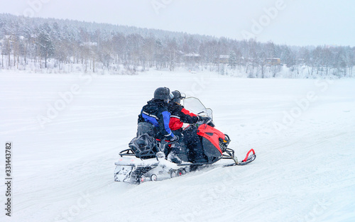People ride snowmobiles in frozen snow lake at winter Rovaniemi