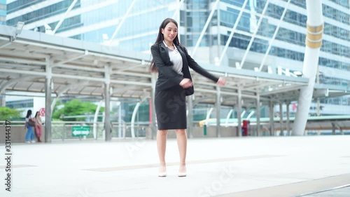 Happy joyful young businesswoman in formal suit dancing victory dancing in the business district photo