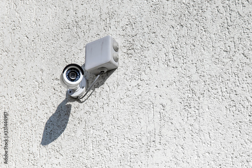 outdoor surveillance camera on a light wall, copy space