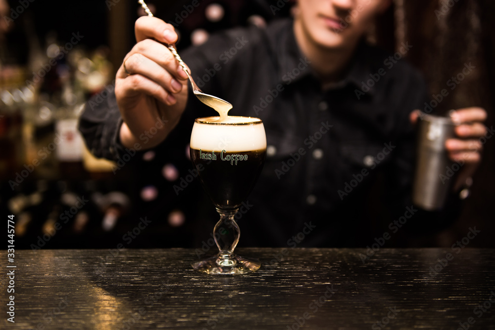 Irish Coffee cups with cream on a dark background, on the bar, warming cocktail, cooking process