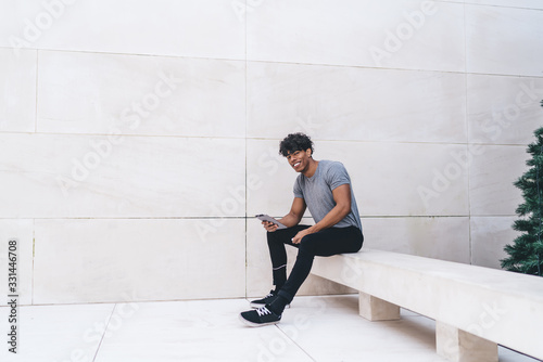 Black man sitting on modern stone bench with tablet