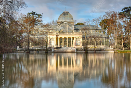Glass Palace, the Crystal Palace in Retiro Park, Madrid, Spain. Historic glass pavilion and former greenhouse. Long exposure landscape view with pond, empty of people.