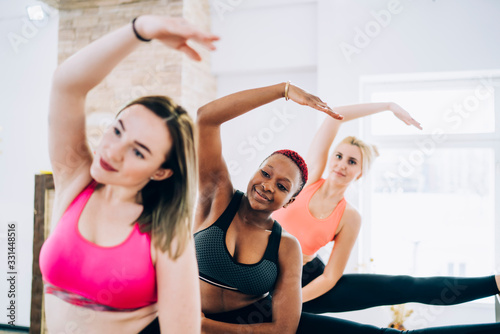 Fototapeta Naklejka Na Ścianę i Meble -  Diverse women stretching back and side muscles on ballet barre