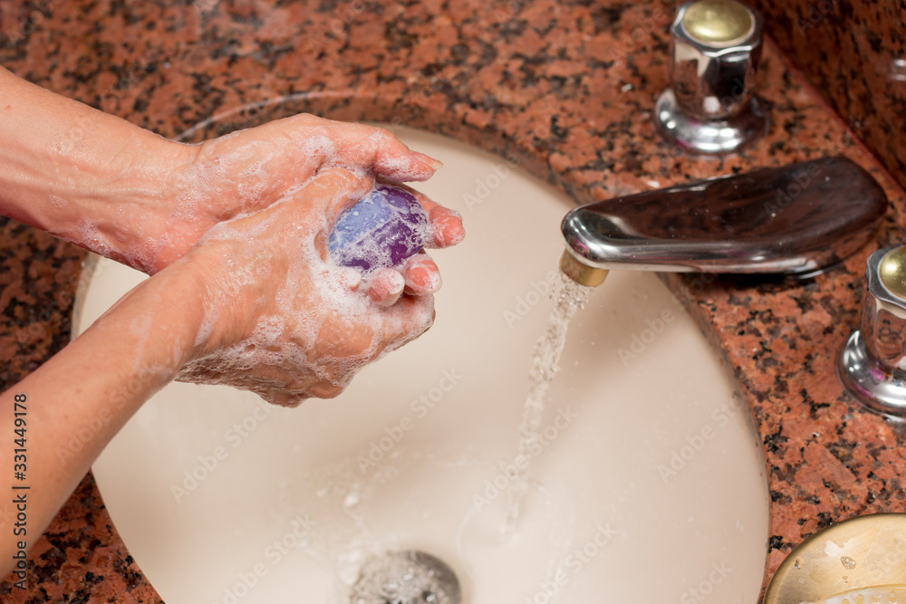 Fototapeta premium Woman Washing her Hands with Soap and Water in the Sink