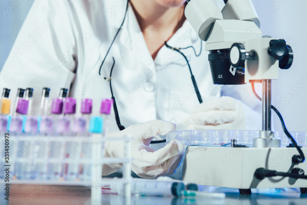 Fototapeta premium Lab technician assistant analyzing a blood sample in test tube at laboratory. Medical, pharmaceutical and scientific research and development concept.