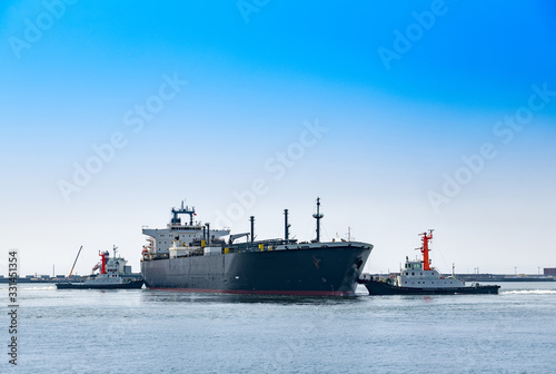 出港する貨物船と綱取り放し作業するタグボート