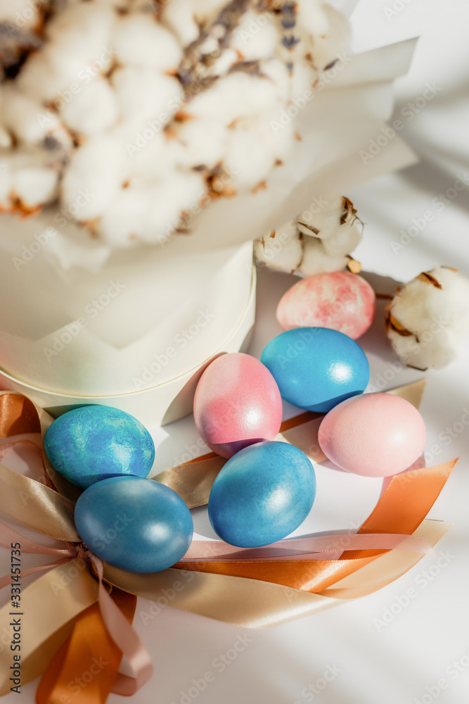 Easter card with dyed eggs and cotton flowers on a white background. Beautiful easter composition. Easter egg hunt. Easter card with dyed eggs and cotton flowers on a white background. Beautiful easter composition. Easter egg hunt.