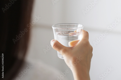 水分補給のためコップ一杯の水を飲む女性
