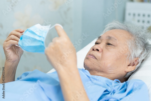Asian senior or elderly old lady woman patient wearing a face mask in hospital for protect infection and kill Novel Coronavirus  2019-nCoV  Covid-19 virus.