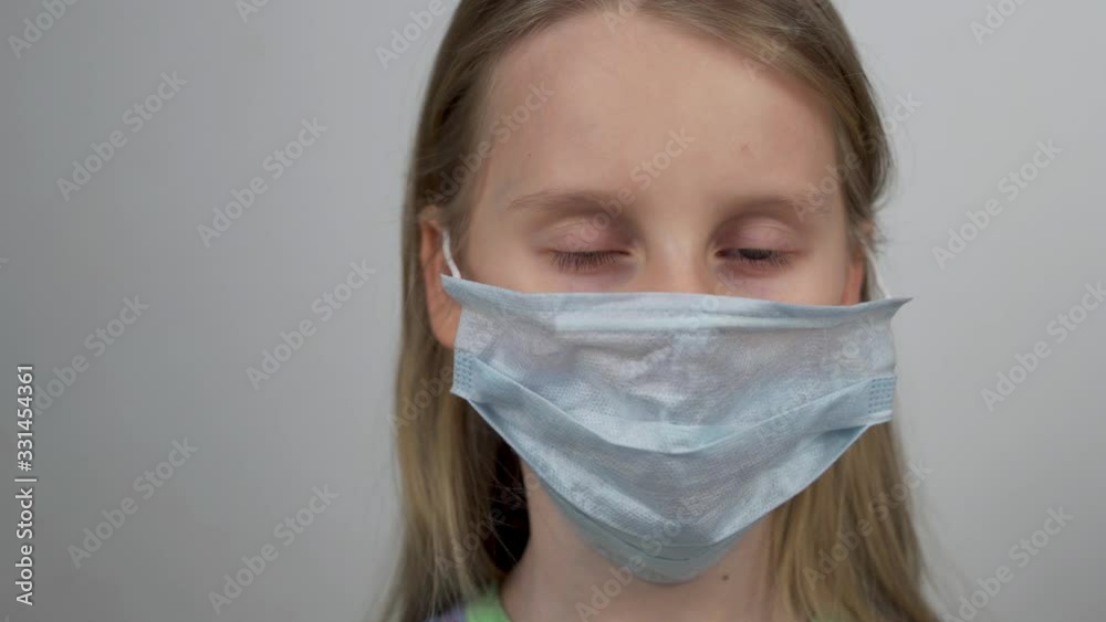Prevention of H1N1 Coronavirus and Viral Infections. The child Puts a Protective Antiviral Mask on his Face. Portrait of a Little Girl, close- Up. Protection from Infection Prevention of H1N1 Coronavirus and Viral Infections. The child Puts a Protective Antiviral Mask on his Face. Portrait of a Little Girl, close- Up. Protection from Infection