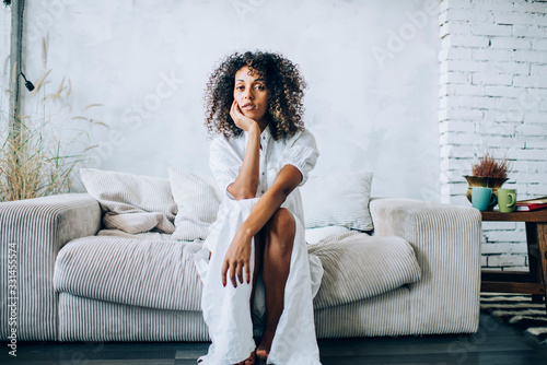 Thoughtful woman sitting on home sofa