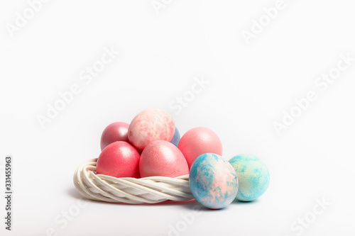 Easter composition with dyed eggs in the nest on a white background. Holiday atmosphere.