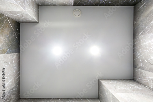 Fototapeta Naklejka Na Ścianę i Meble -  suspended ceiling with led lightspot lamps and drywall construction in empty room in apartment or house. Stretch ceiling white and complex shape. looking up