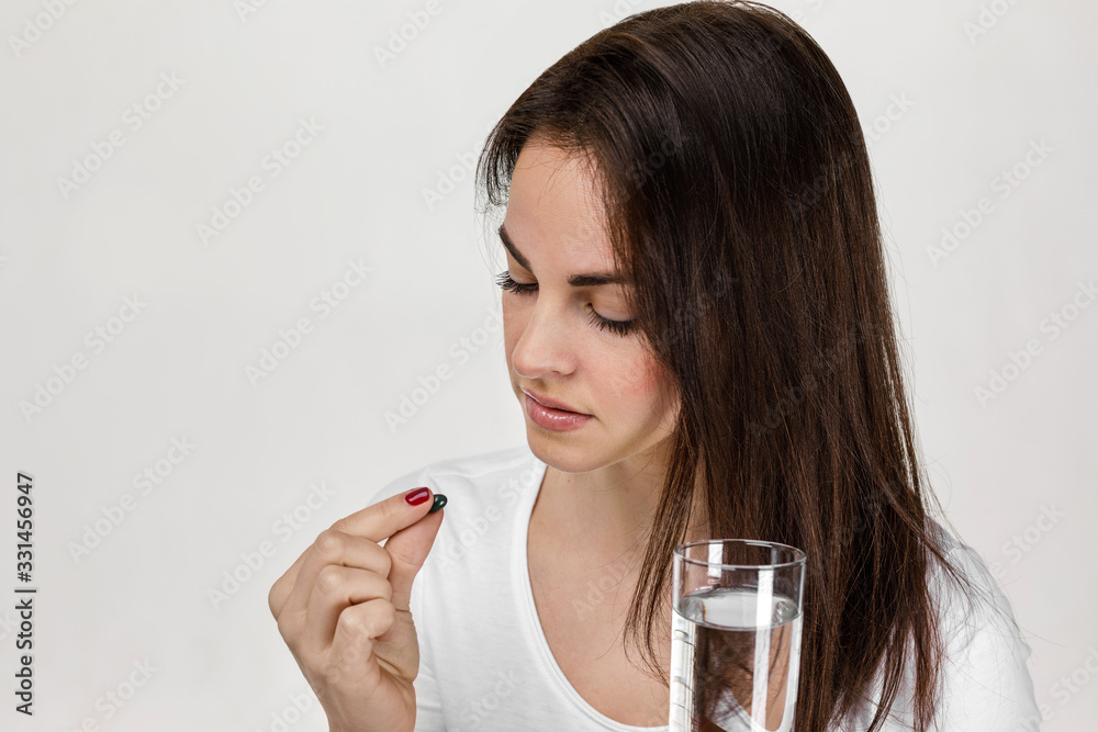 Sick woman feel unwell holding glass of water and taking pill painkiller medicine from headache or pain Sick woman feel unwell holding glass of water and taking pill painkiller medicine from headache or pain