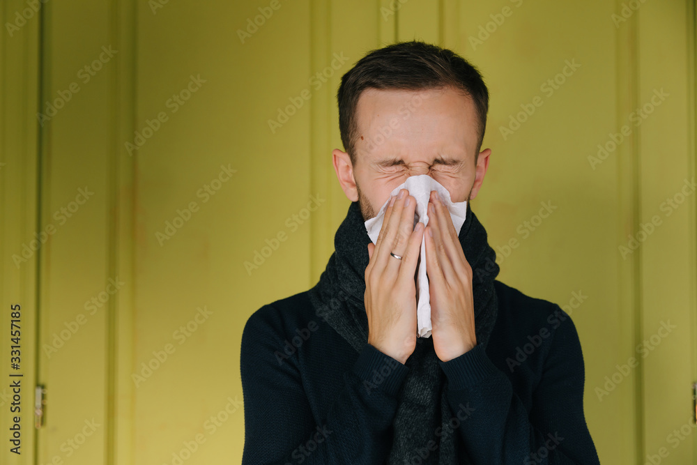 Sick young caucasian man on green background use handkerchief bl Sick young caucasian man on green background use handkerchief bl