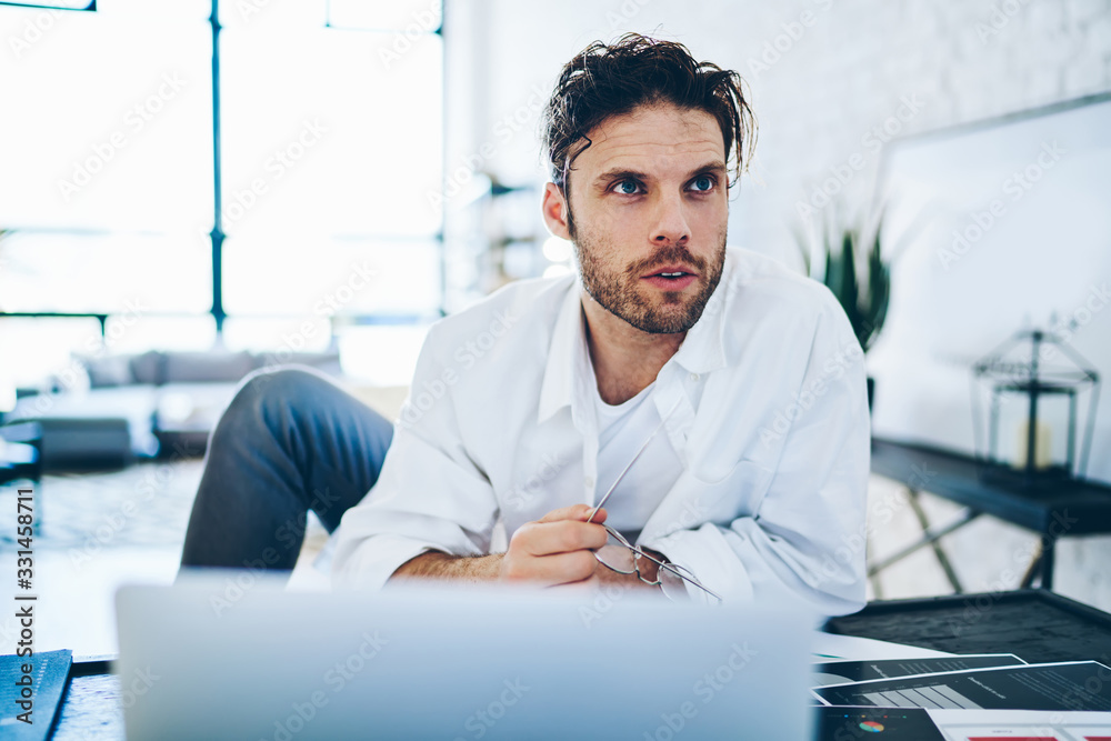 Fototapeta premium Concerned businessman working on project in apartment