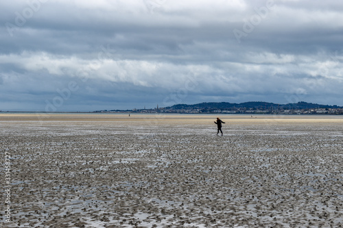 Photography A woman maintaining social distancing walking outdoors on the beach in Dublin, I