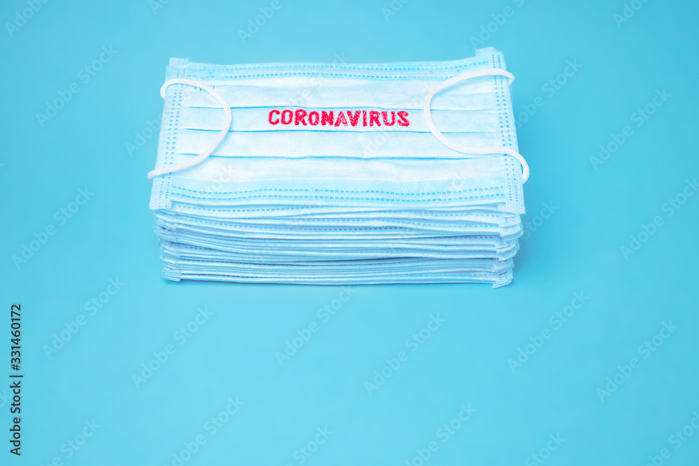 Coronavirus background. Epidemic backround. Facial mask in the pile. Quarantine background. Healthcare background. Blue medical disposable face mask with covid-19 print. Facial mask wholesale, in pile