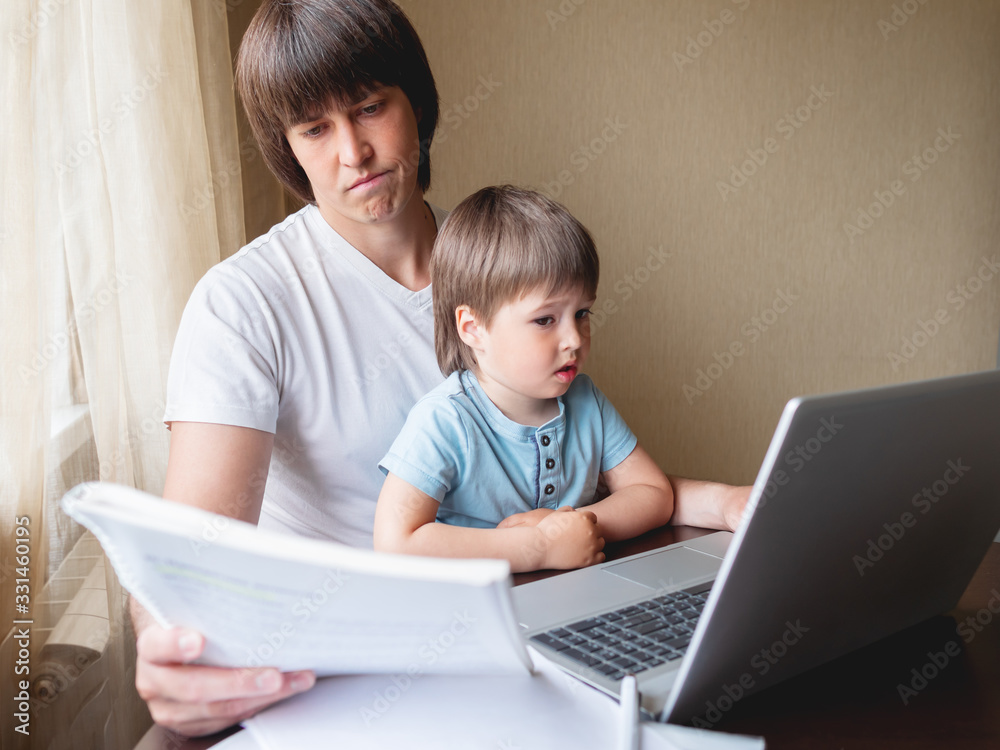 Self-isolation because of coronavirus outbreak. Man is remote working with his little son. Laptop on table. Self-isolation because of coronavirus outbreak. Man is remote working with his little son. Laptop on table.
