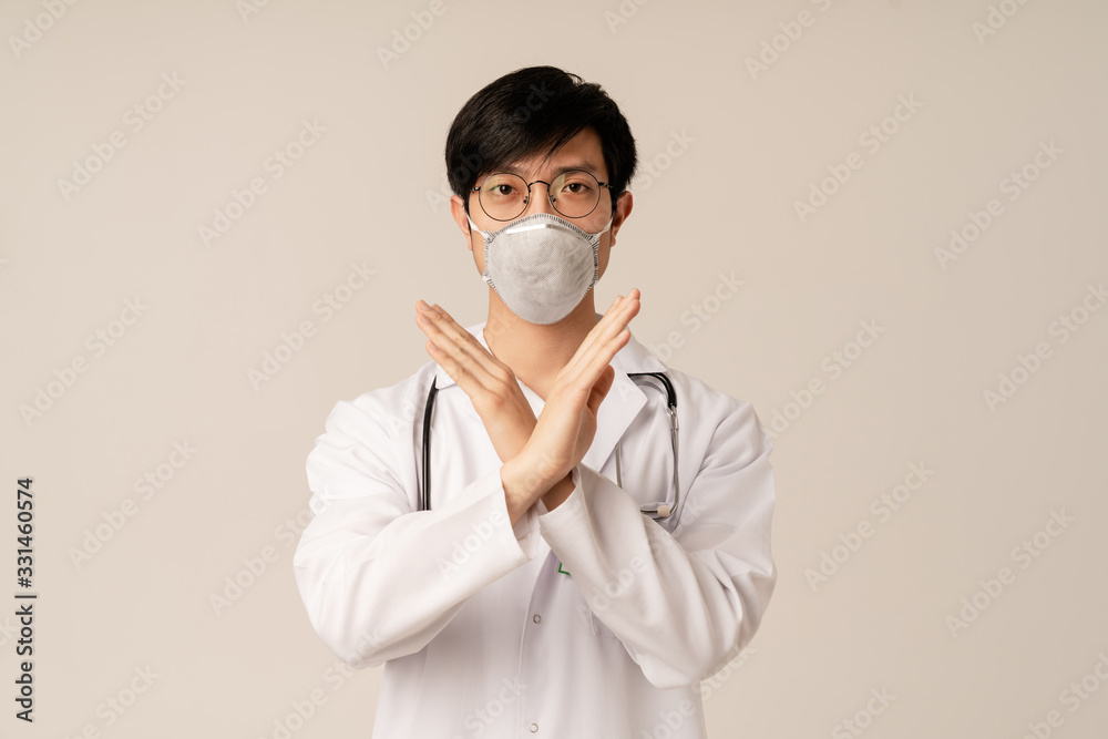 Image of asian doctor in uniform and protective mask doing stop gesture Image of asian doctor in uniform and protective mask doing stop gesture