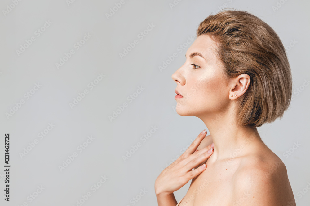 young beautiful blonde side view in a studio on a light background. No retouching. Natural beauty concept