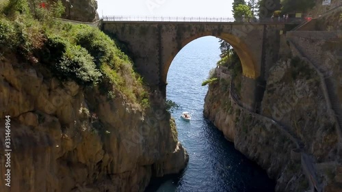 Fiordo di Furore village arch bridge leading to Mediterranean sea, a boat is standing by, Amalfi coast Italy, Aerial dolly in reveal shot