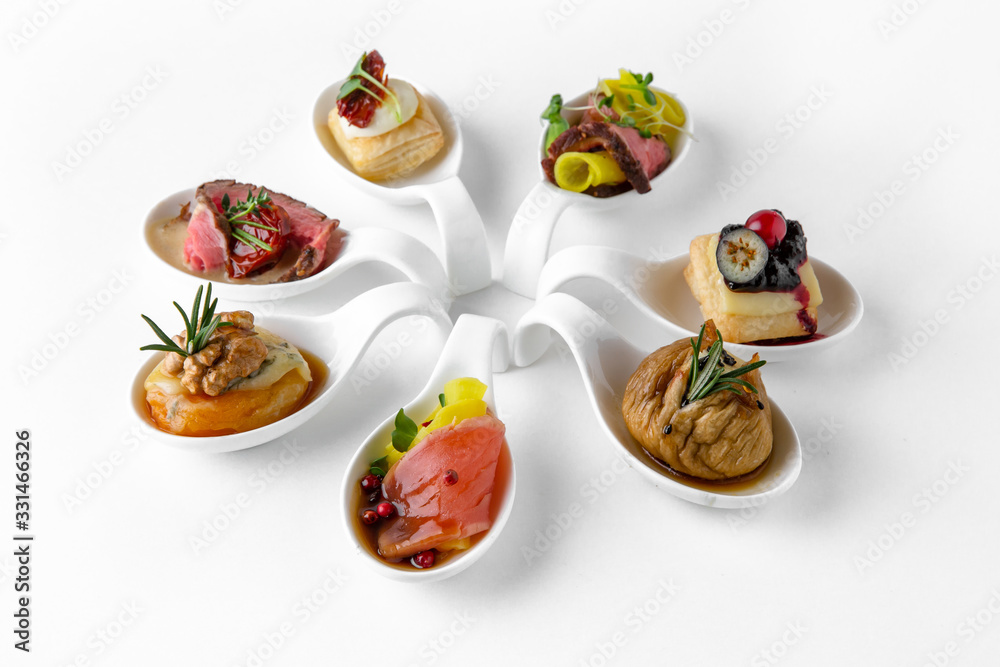 Assorted portions of different salmon, dried fruit, cold cuts and cheese snacks. Beautifully decorated catering banquet menu. Food snacks and appetizers for buffet. Isolated on white background Assorted portions of different salmon, dried fruit, cold cuts and cheese snacks. Beautifully decorated catering banquet menu. Food snacks and appetizers for buffet. Isolated on white background