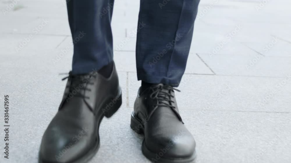 Businessman legs walking on city street.Entrepreneur wearing black leather shoes Businessman legs walking on city street.Entrepreneur wearing black leather shoes