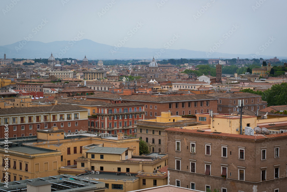 View of the city from a height. Panorama of Rome, Italy on a cloudy day. Mountain silhouettes on the horizon.